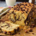 A close up of a nutella swirl loaf cake with the first slice lying down and on brown baking paper