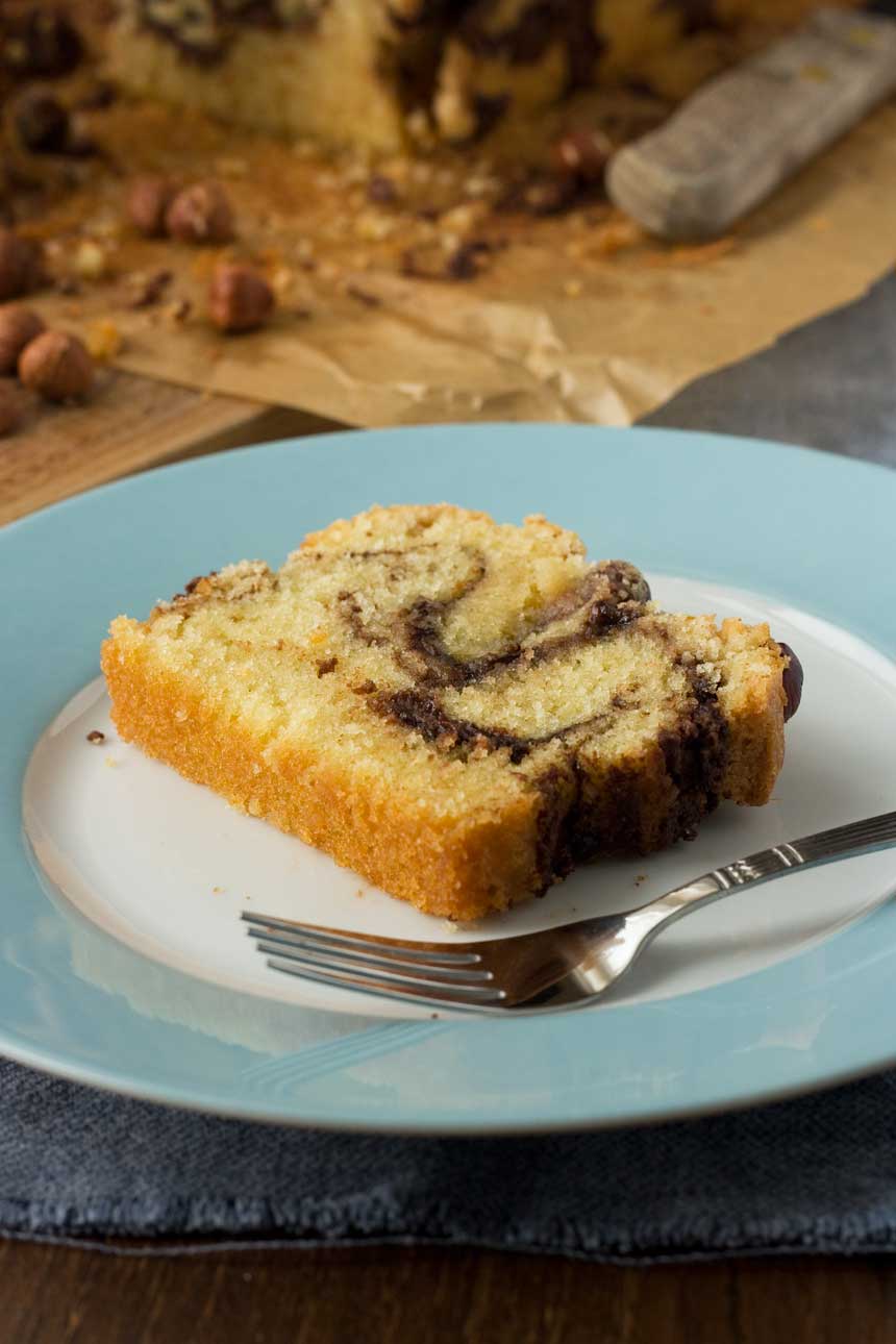 A slice of Nutella swirl loaf cake on a blue and white plate with a fork