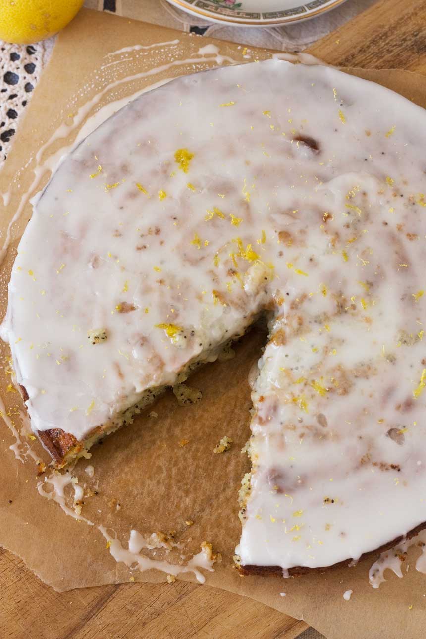 Lemon poppy seed drizzle cake with a big piece cut out of it photographed from above.