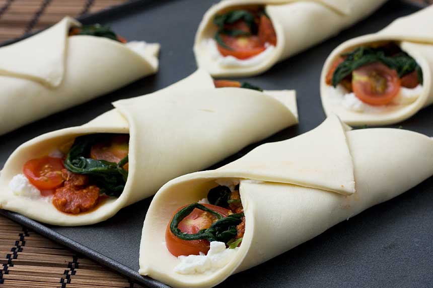 Ricotta, cherry tomato and chorizo puff pastry tarts on a baking tray ready to be baked.