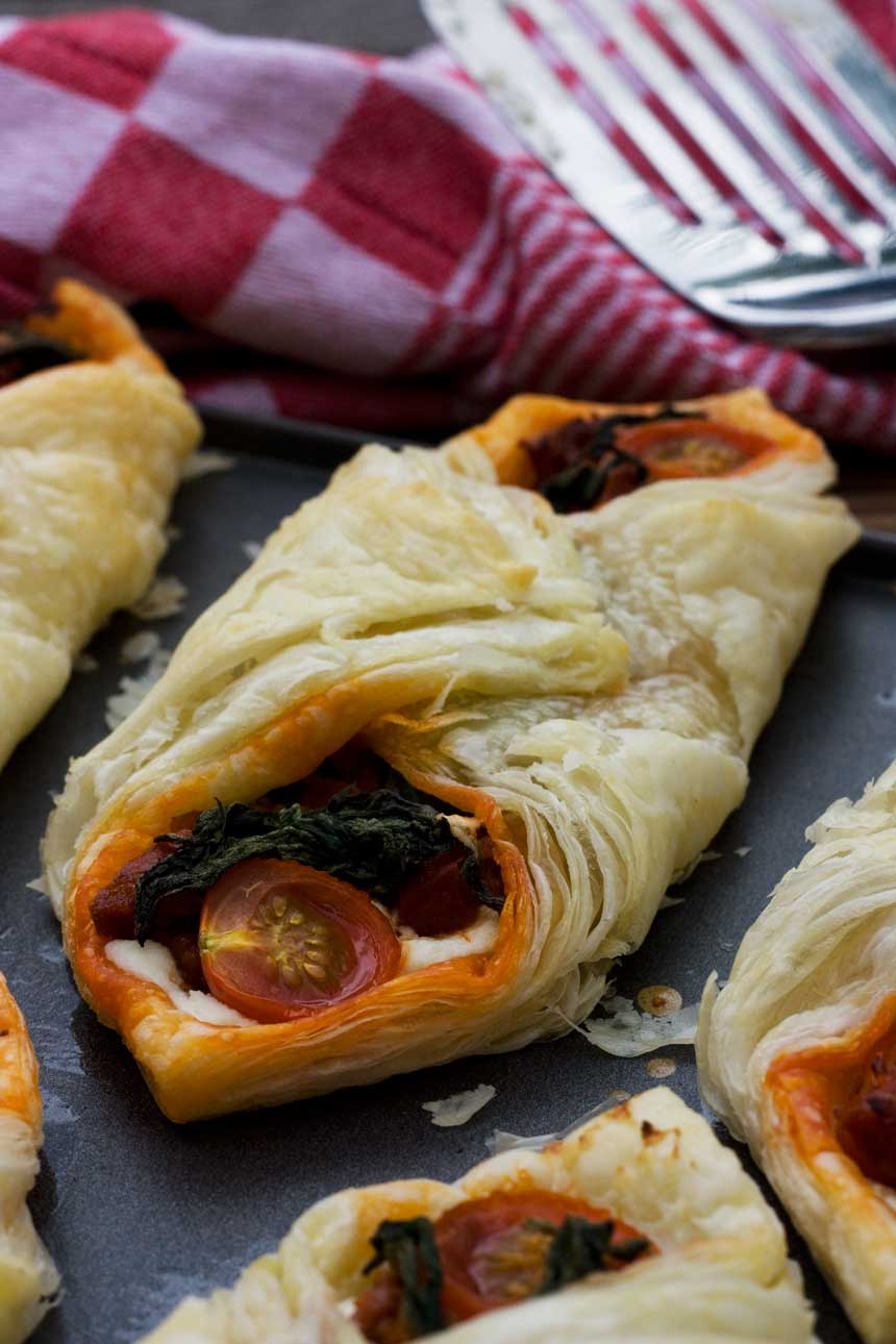 closeup of a Ricotta, cherry tomato and chorizo puff pastry tart on a baking tray.