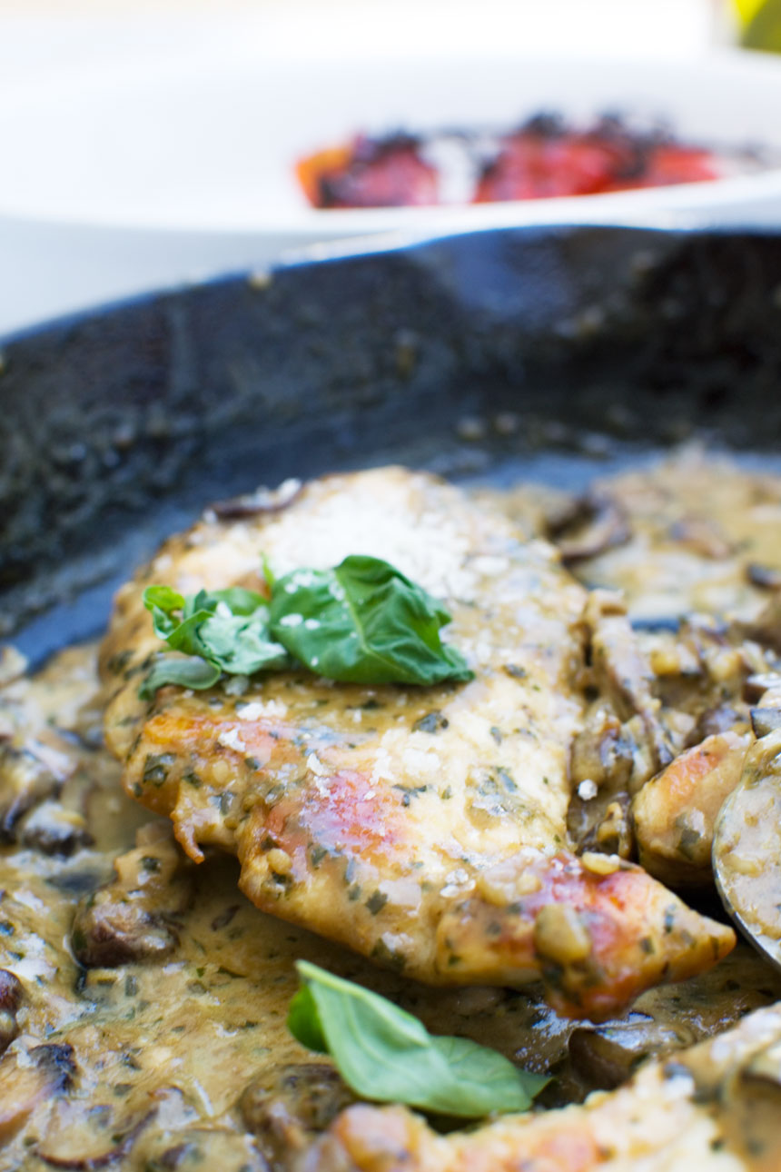 Close up of creamy pesto chicken with parmesan and mushrooms in a cast iron pan