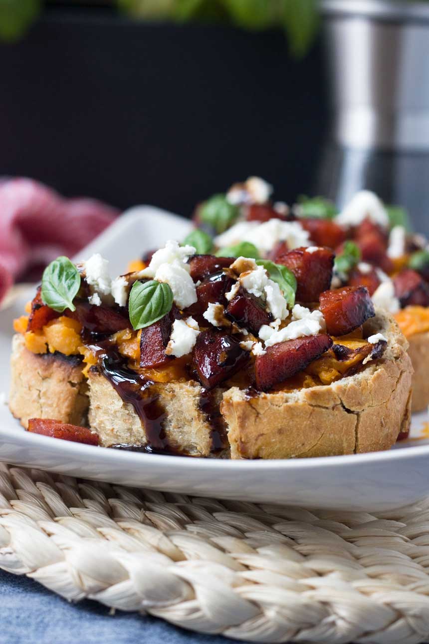 A close up of a white platter of Bruschetta with sweet potato and Chorizo.