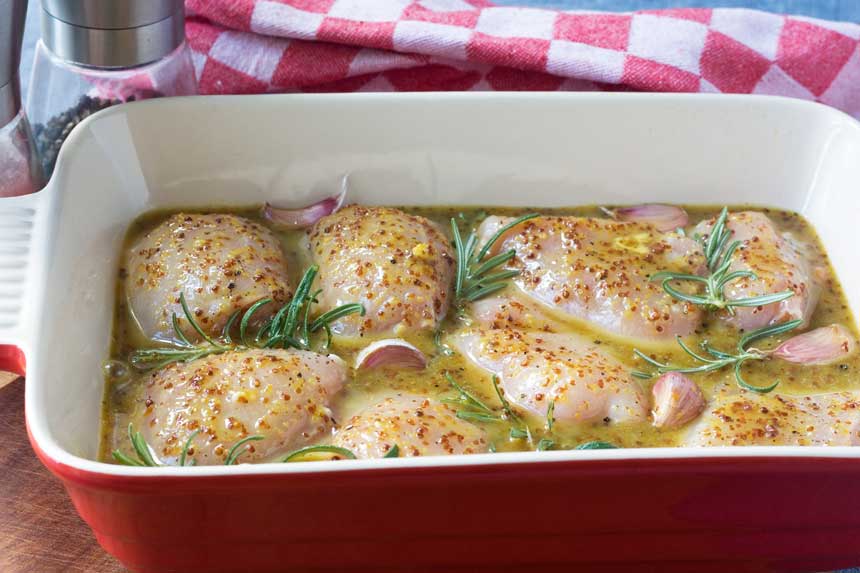 Ingredients for baked honey mustard chicken in a red baking dish before going in the oven.