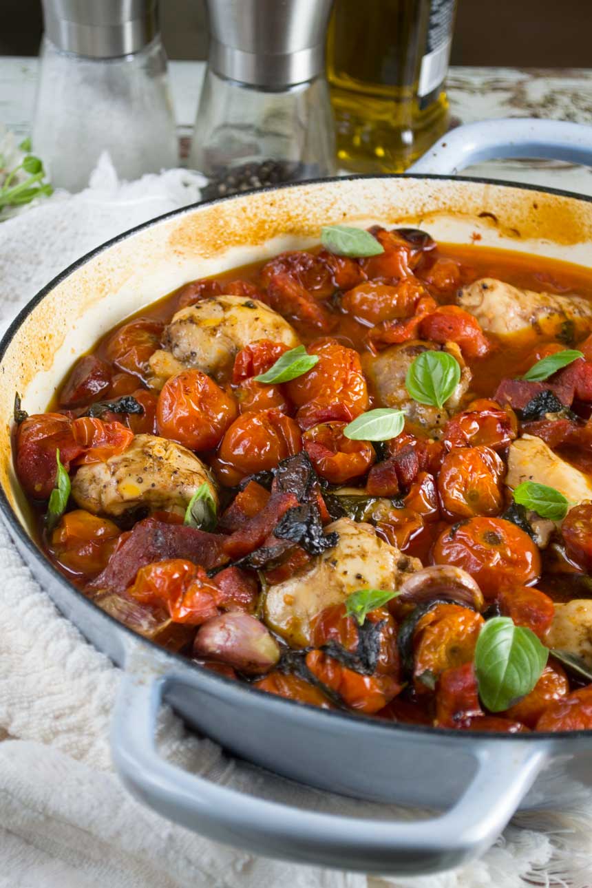 A closeup of one pan chicken and chorizo with cherry tomatoes in a blue cast iron pan.