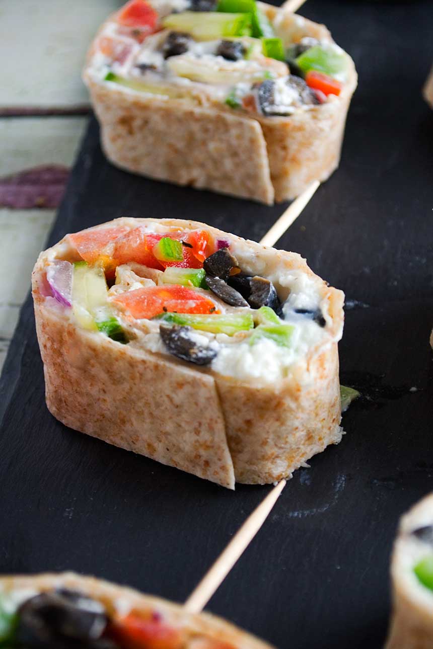 Greek tortilla pinwheels on a black slate platter