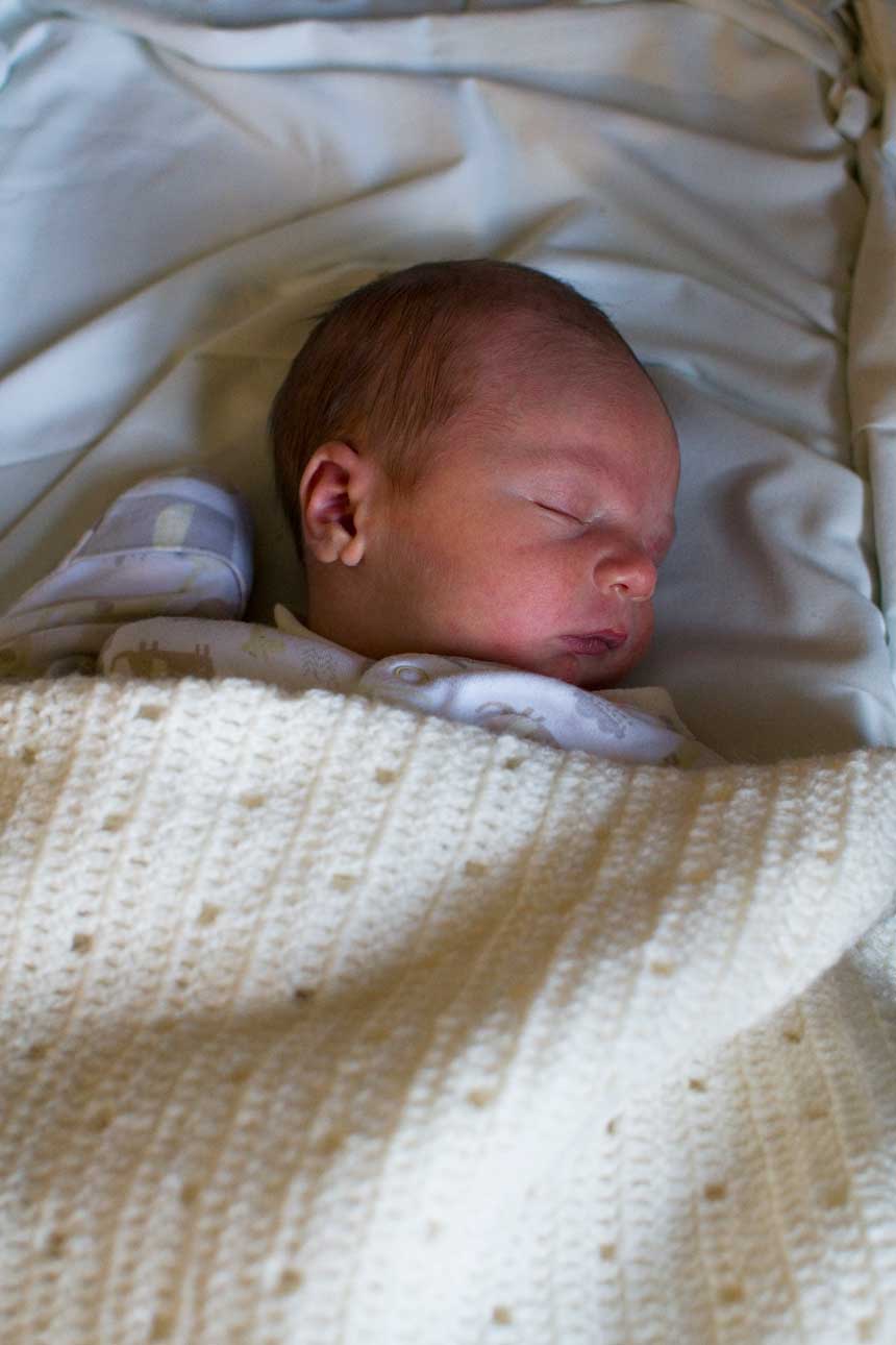 A newborn baby asleep in a bassinet.