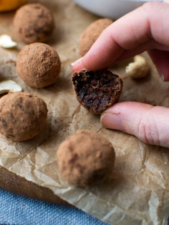 5-ingredient healthy chocolate orange truffles in a white bowl on baking paper with more truffles scattered around
