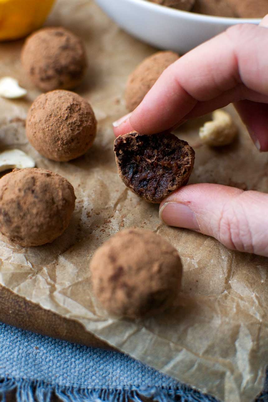 5-ingredient healthy chocolate orange truffles in a white bowl on baking paper with more truffles scattered around