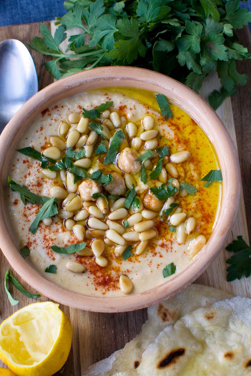 Quick hummus in a brown ceramic pot from above.