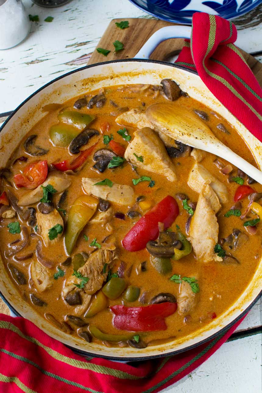 Paprika chicken in a cast iron pan from above and with a spoon in it.