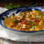 A horizontal image of a dish of Thai Massaman chicken curry with sweet potatoes and peanuts