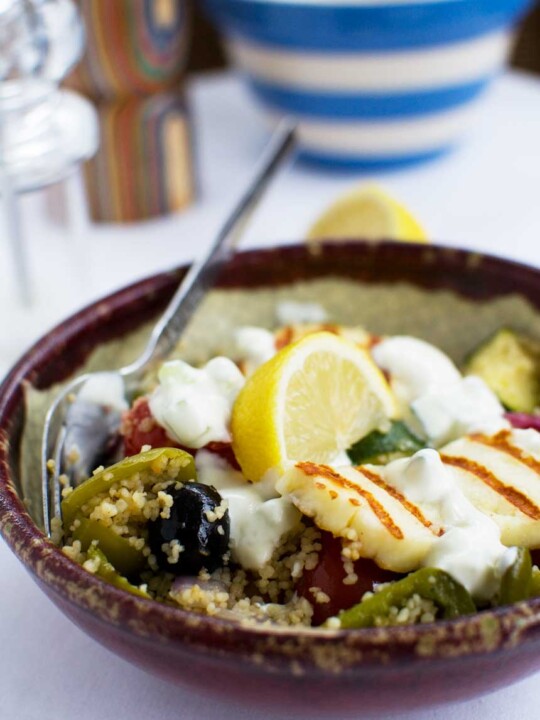 A bowl of Greek couscous with halloumi with a spoon in it