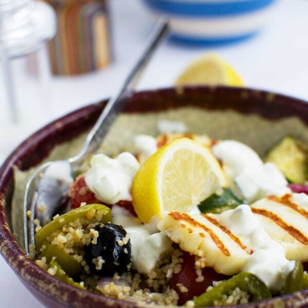 A bowl of Greek couscous with halloumi with a spoon in it