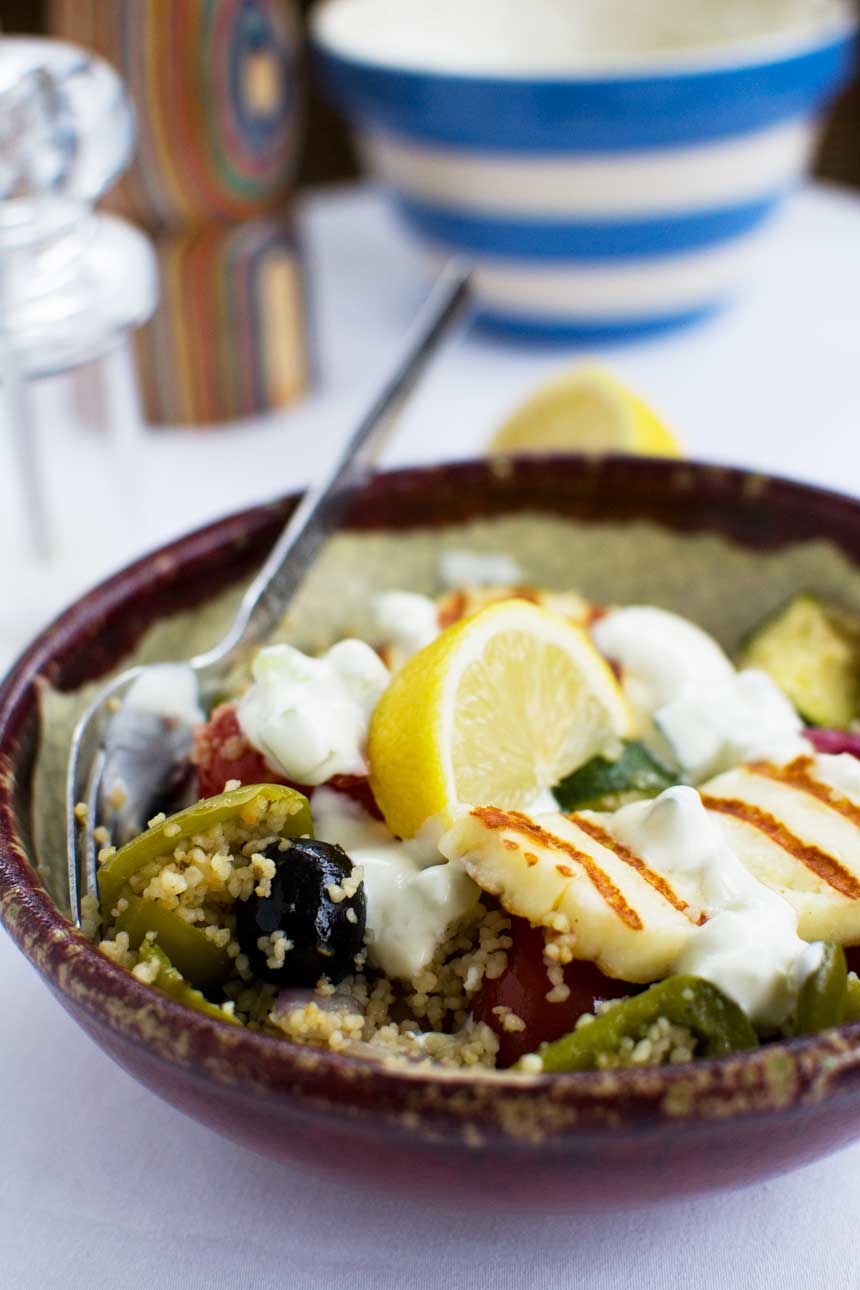 A bowl of Greek couscous with halloumi with a spoon in it