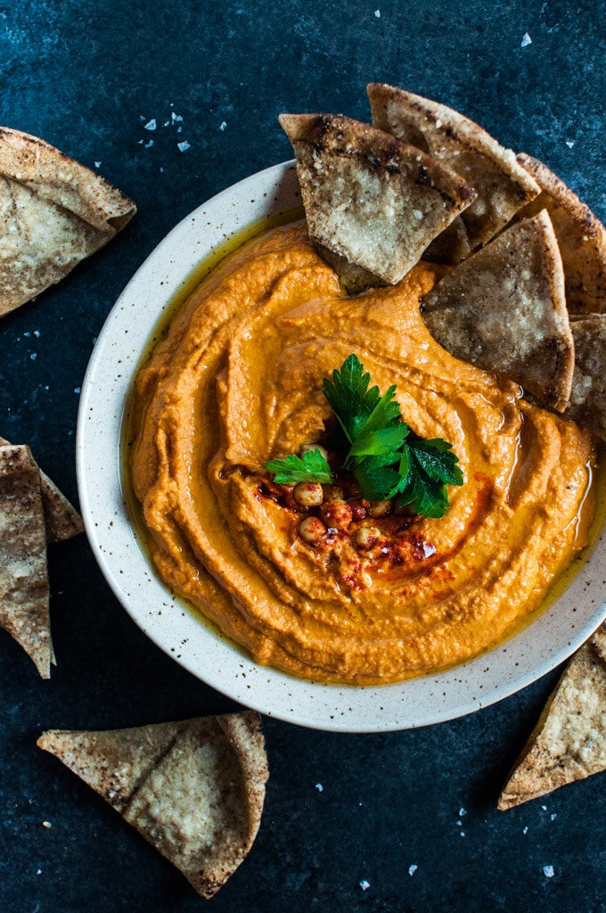 A close up of a bowl of red pepper hummus from above.