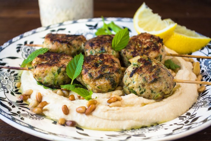 A plate of food on a table with Hummus and Meatballs on it