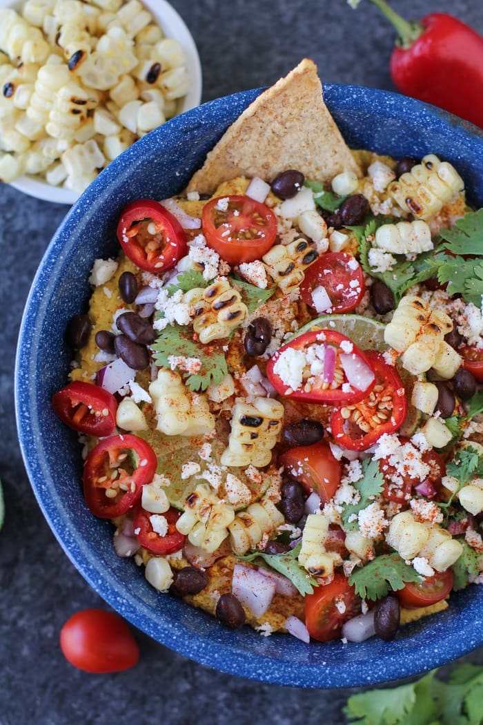 A colorful plate of Mexican street corn hummus in a blue bowl