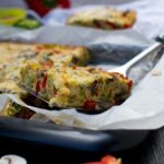 Someone lifting a piece of frittata out of a baking pan.