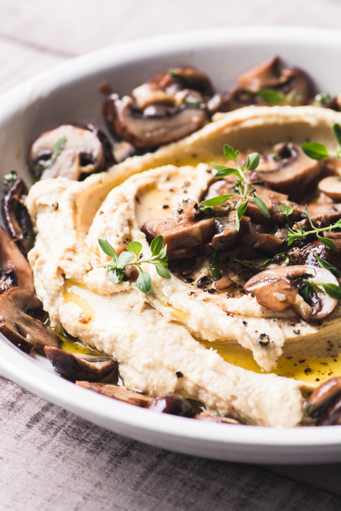 A closeup image of a plate of Hummus and Mushrooms.