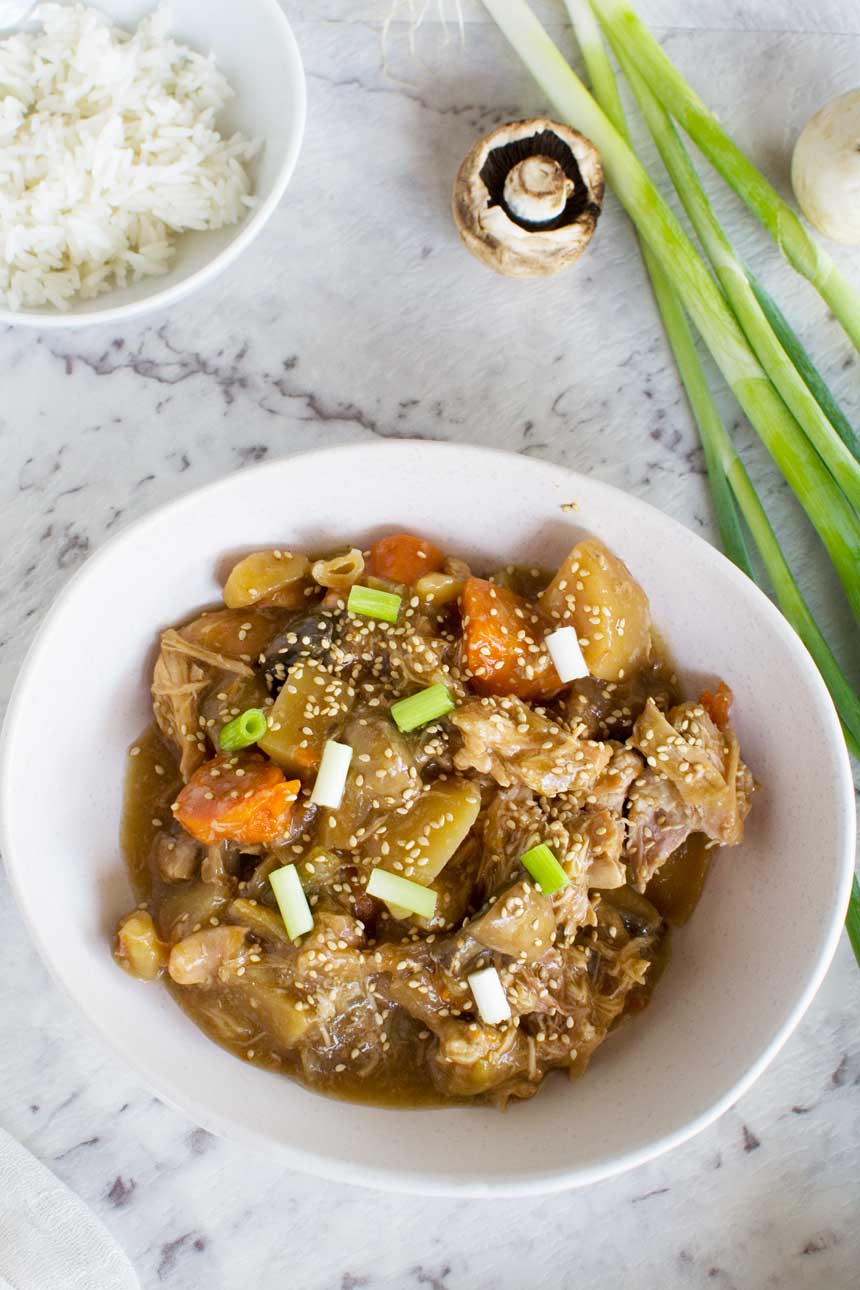 Slow cooker Korean chicken in a white bowl from above with ingredients.