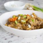 Slow cooker Korean chicken in a white bowl on a marble background.