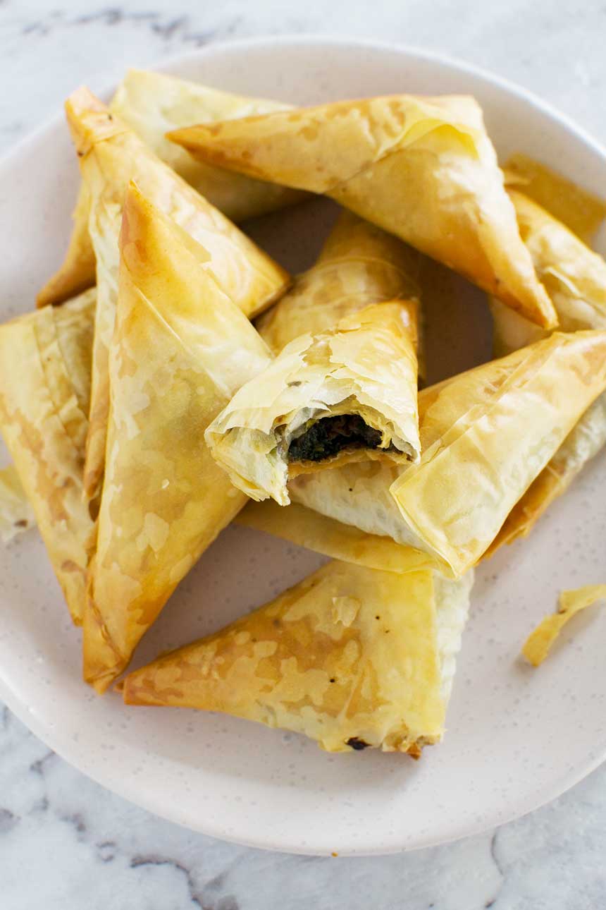 Crispy mushroom filo parcels on top of each other on a white plate from above.