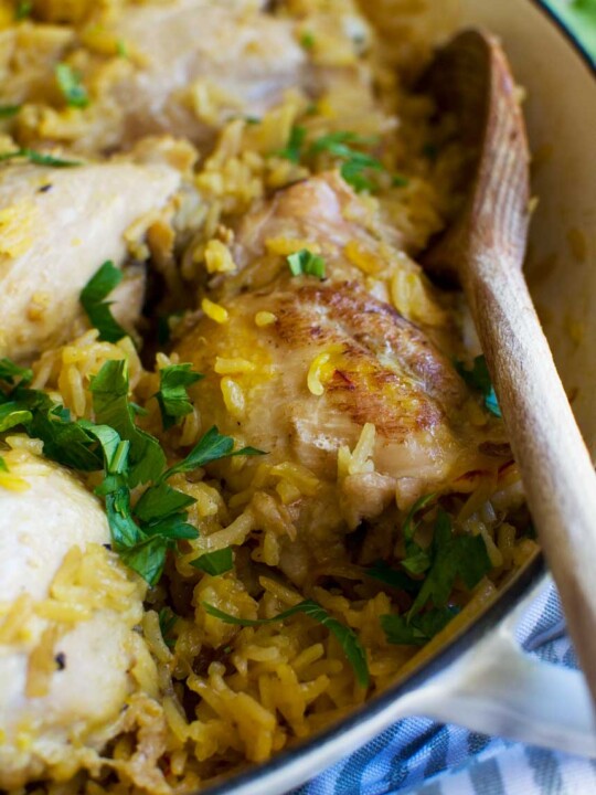 A close up of a dish of stovetop chicken and rice with a wooden spoon in it.