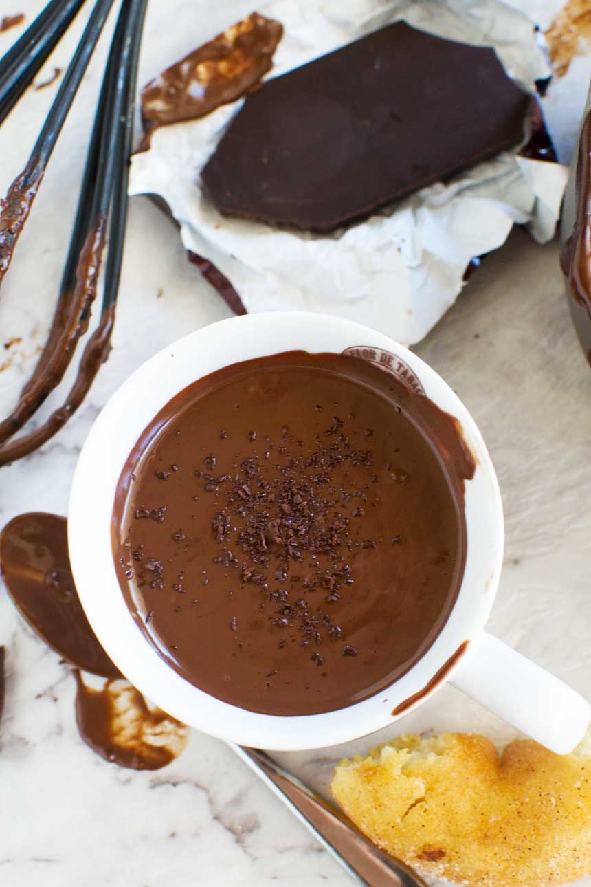 A cup of thick hot chocolate from above with kitchen equipment and ingredients all around.