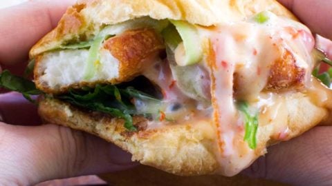 Someone eating a crispy halloumi burger up close