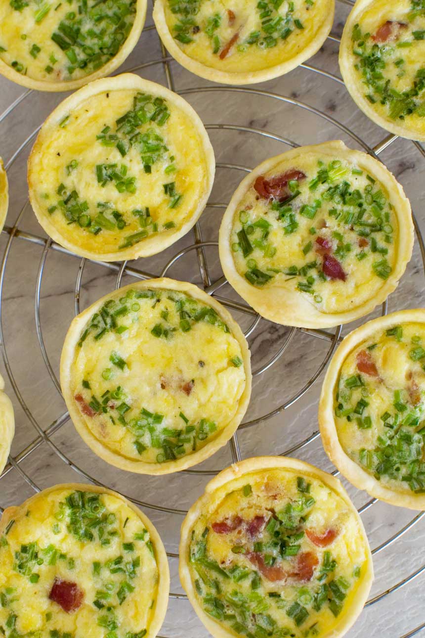 Mini quiches on a cooling rack from above and on a marble background.