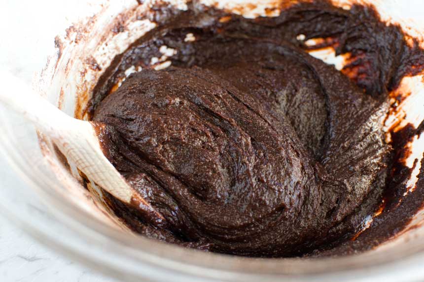 A bowl of gooey Swedish chocolate cake batter with a wooden spoon in it.