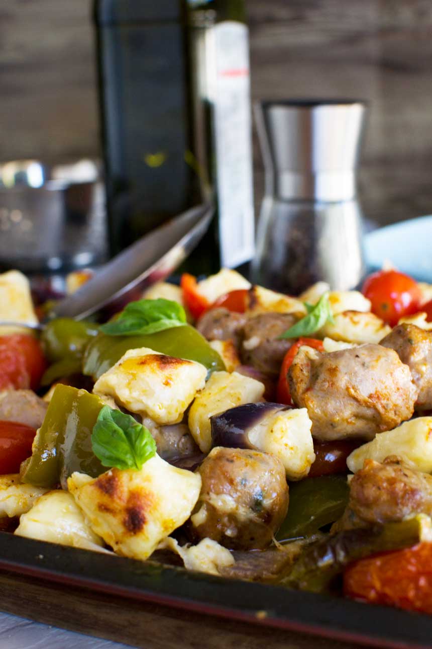 Easy baked gnocchi with sausage, peppers and tomatoes up close on the baking tray.