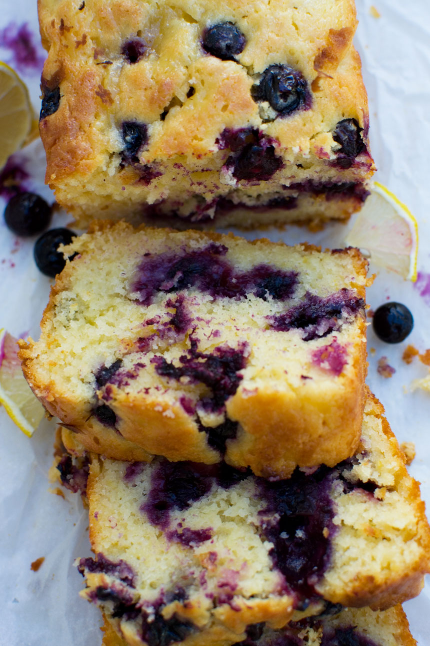 A close up of slices of sticky blueberry lemon curd cake on baking paper from above.