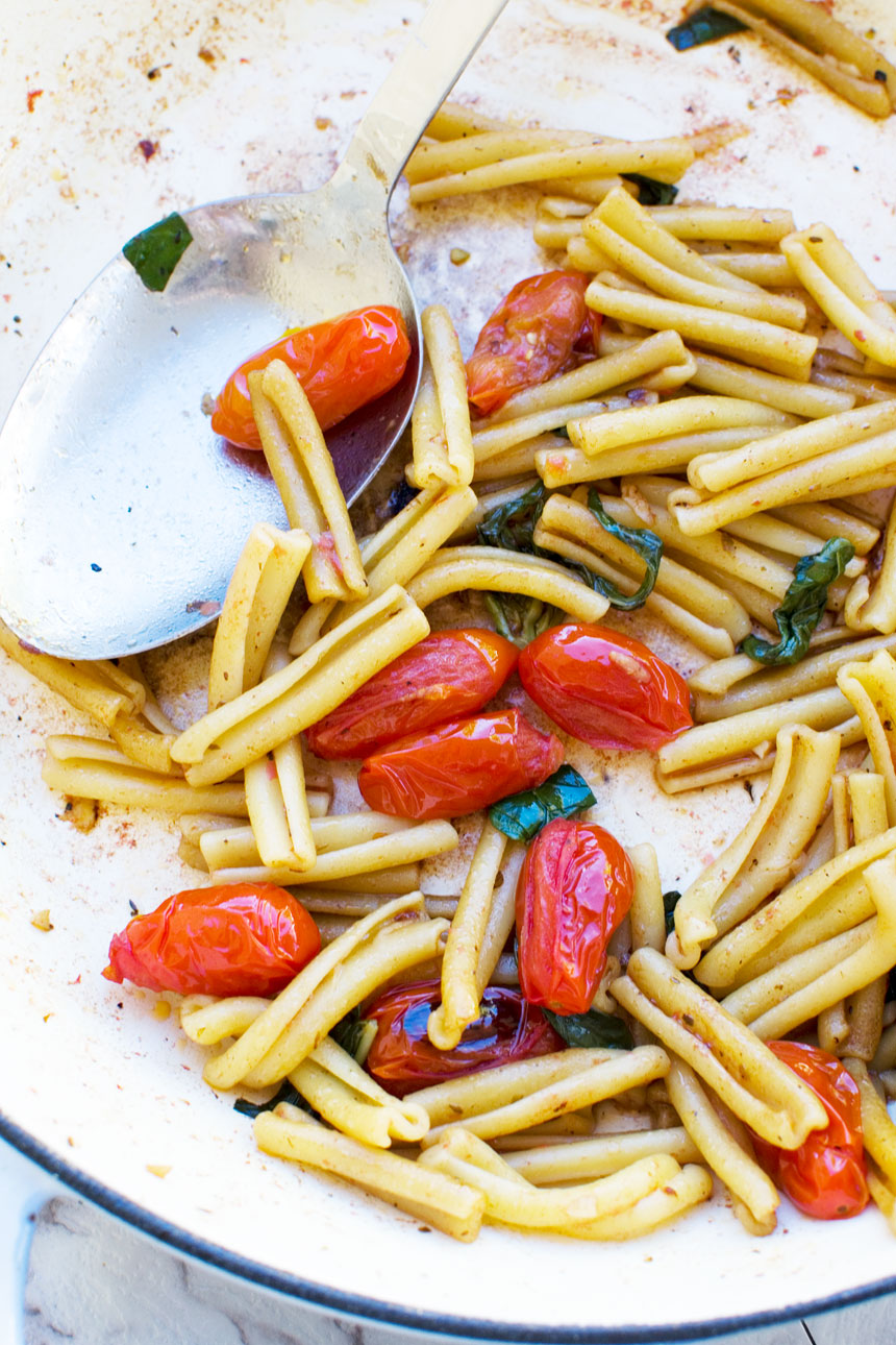 Closeup of 12-minute cherry tomato pasta in a pan with a spoon from above.