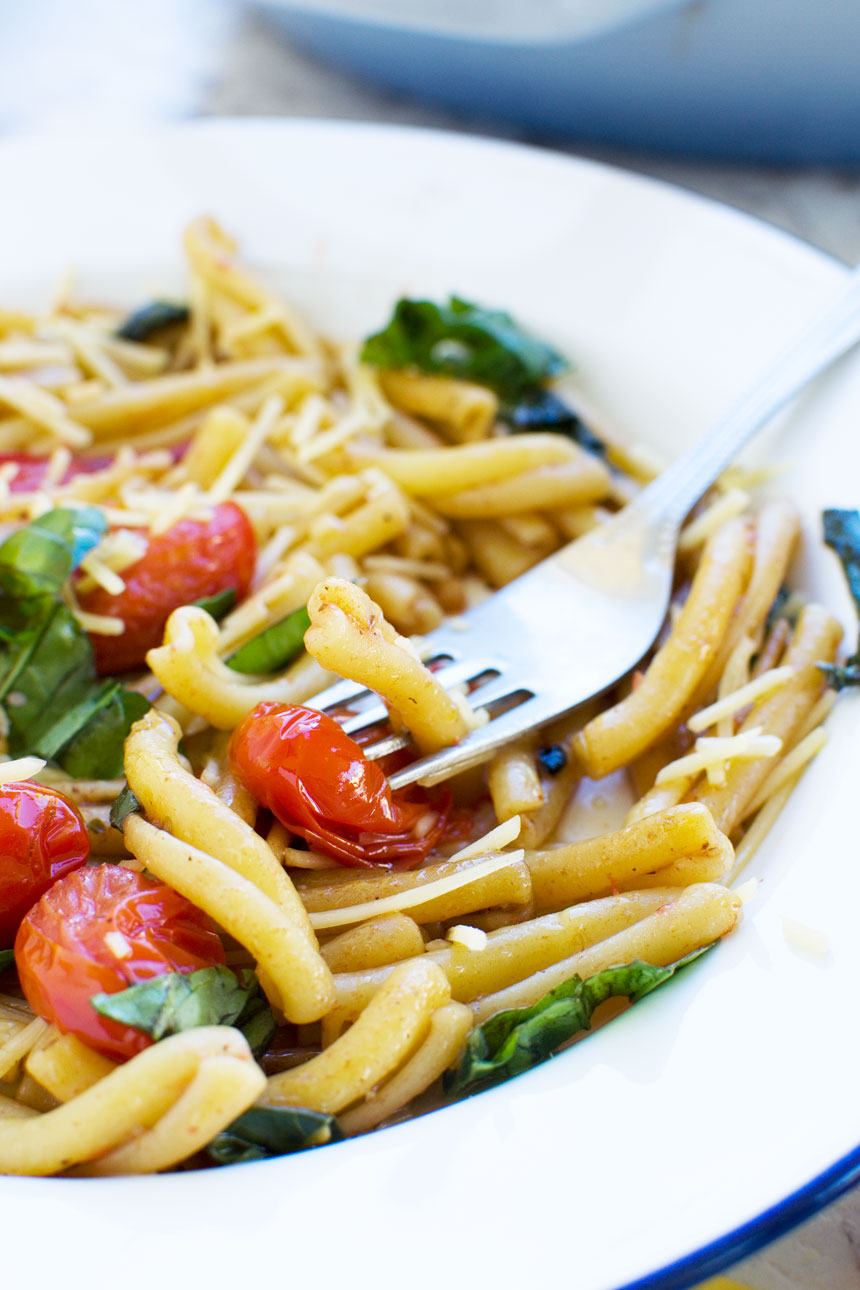 closeup of 12-minute cherry tomato pasta in a white bowl with a fork.