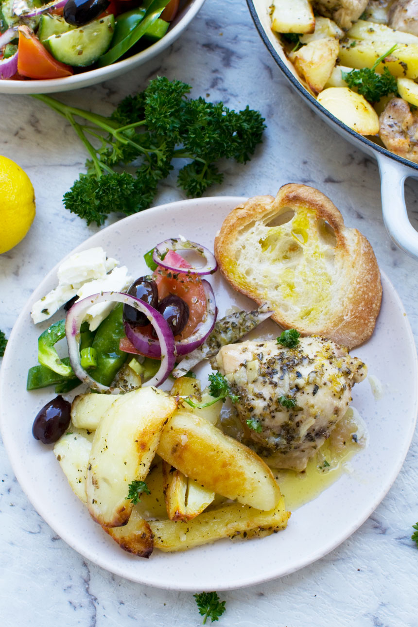 A plate of Greek roasted chicken & potatoes with a Greek salad from above