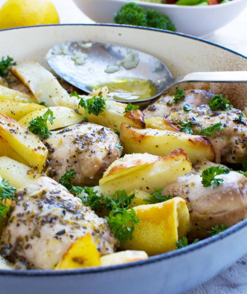 One pan Greek baked chicken & potatoes with a Greek salad in the background