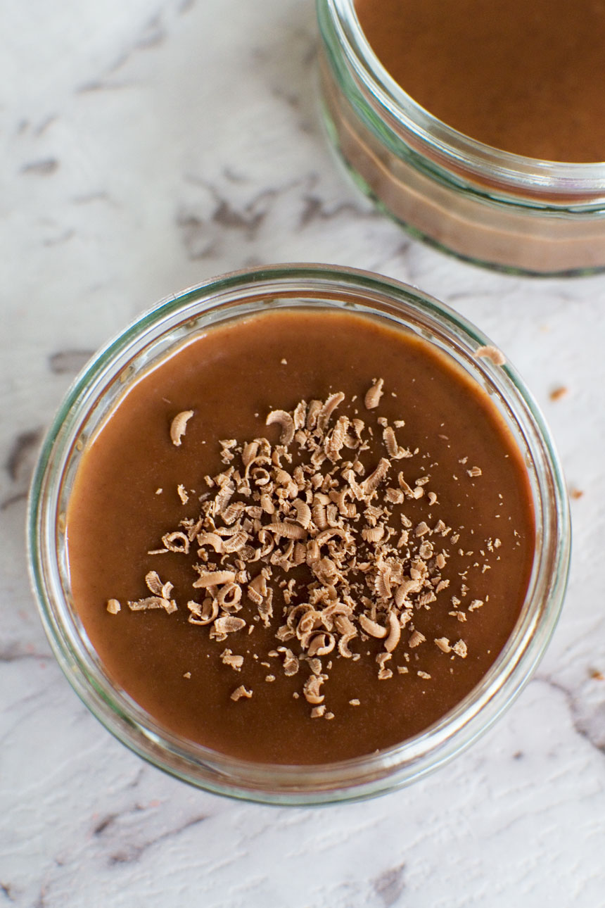 A chocolate pot with grated chocolate on the top from above on a marble background.