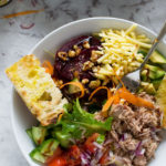 View from above of an easy tuna salad with a spoon in it and on a marble background.
