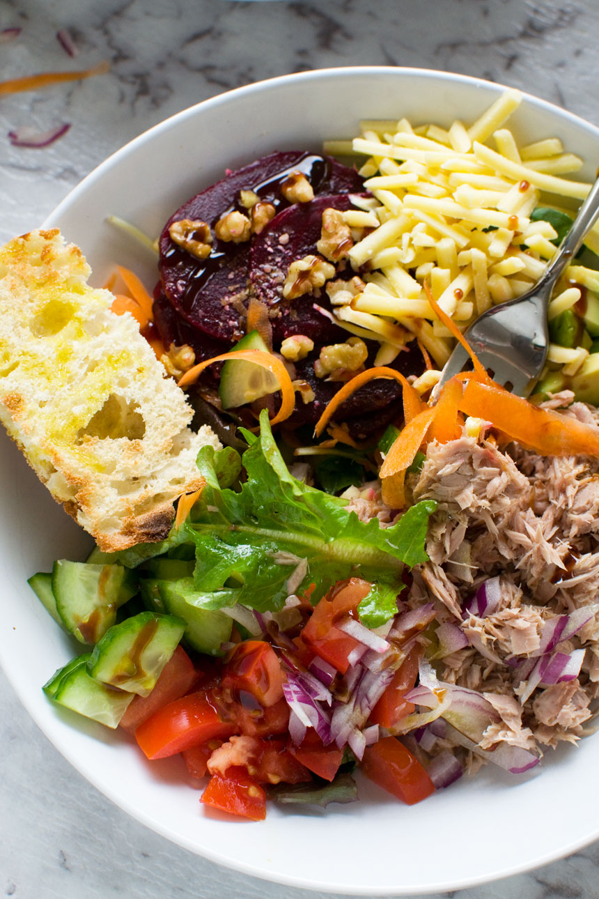 Closeup of the edge of a white bowl of easy tuna salad with a fork in it.