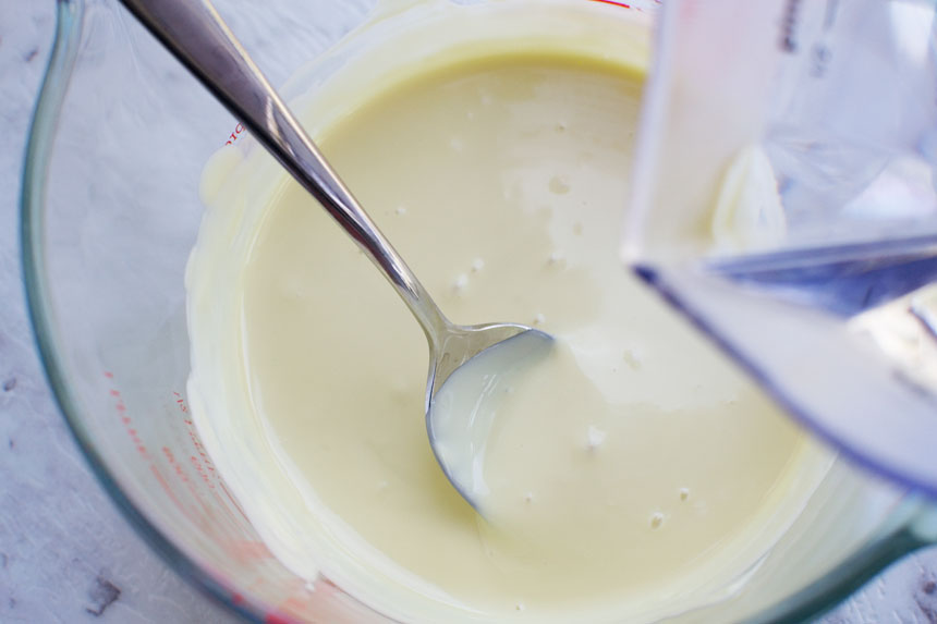 Melted chocolate in a jug with a spoon from above.