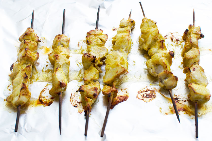 Chicken satay skewers on foil just after being cooked.