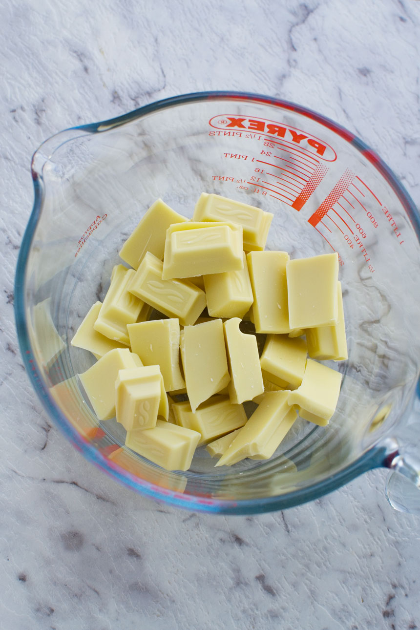 White chocolate in a Pyrex jug from above on a marble background.