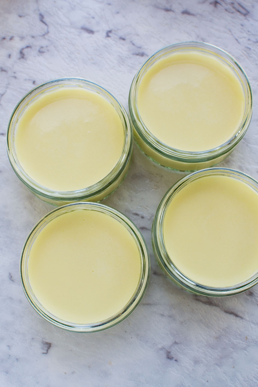 4 white chocolate pots de creme from above on a white marble background.