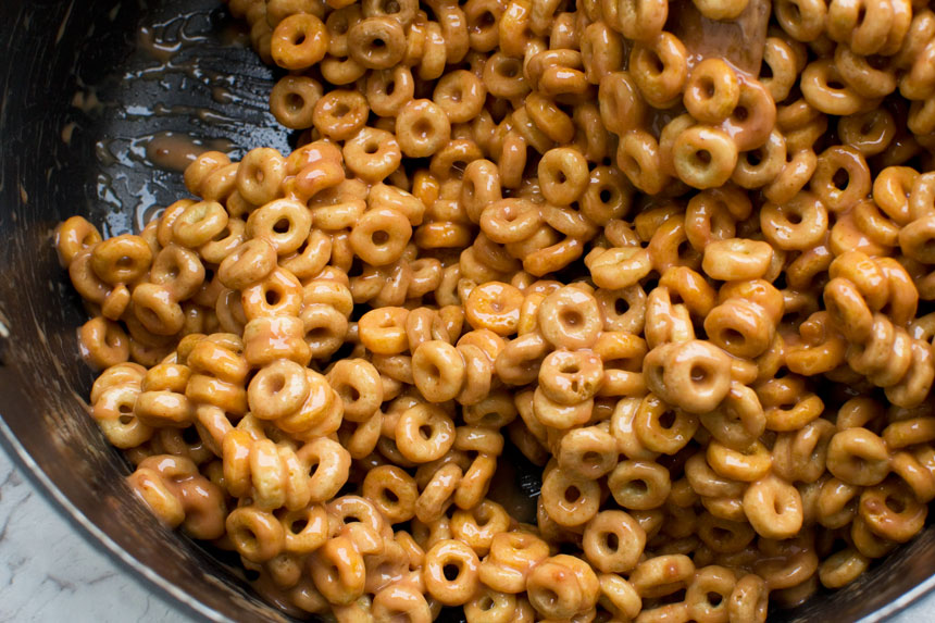 Closeup of the mixture for peanut butter cheerio bars in a pan from above