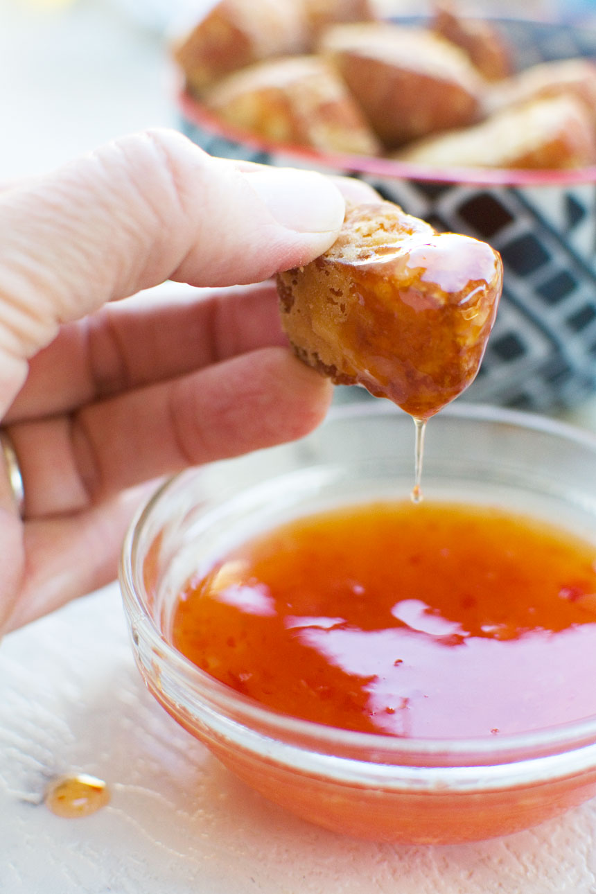 someone dipping a fried halloumi bite in a small dish of sweet chili sauce