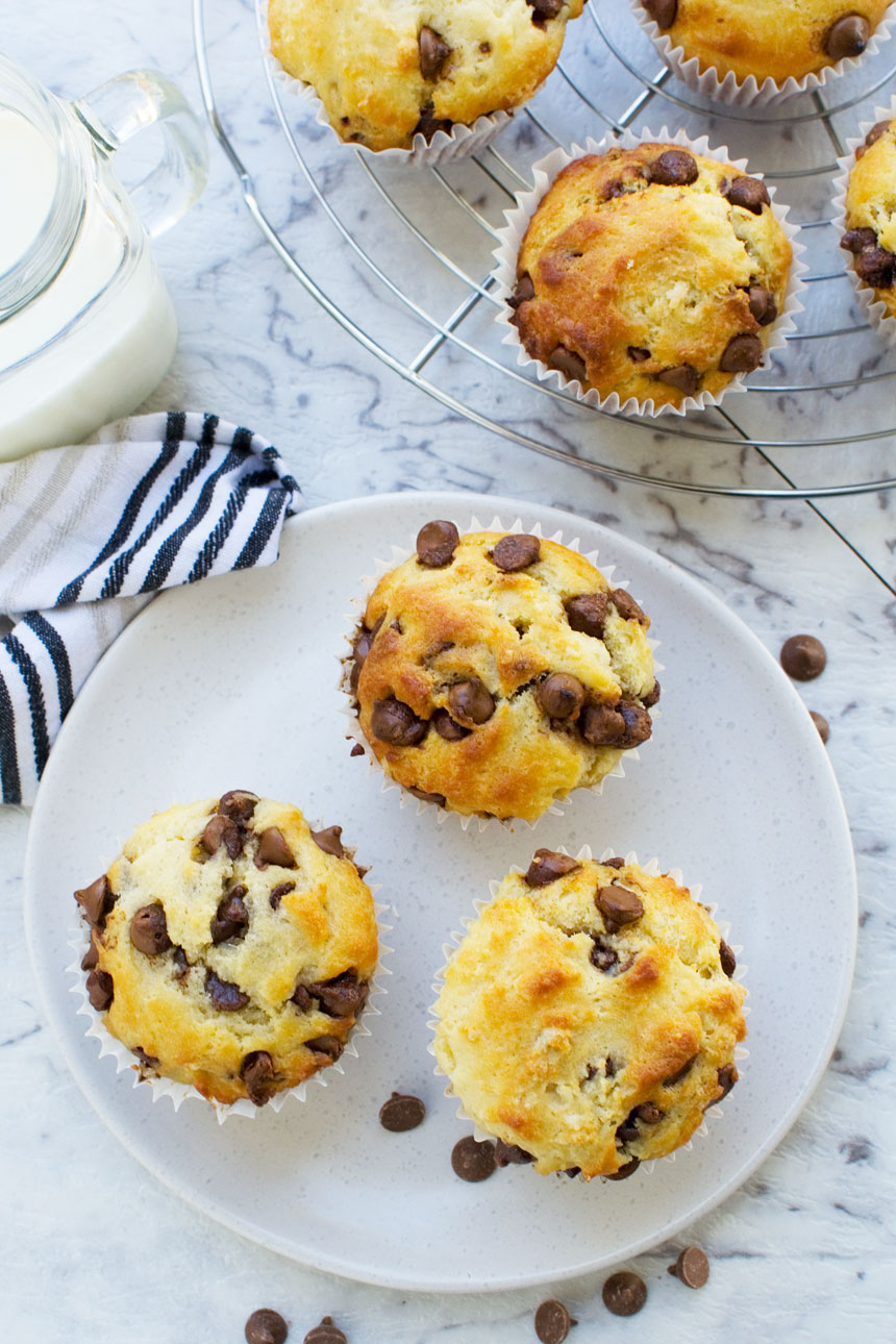 Greek yogurt choc chip muffins on a white plate from above with more on a cooling rack in the corner