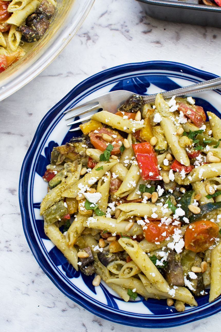 Mediterranean penne pasta salad in a blue bowl from above on a marble background and with a fork in it