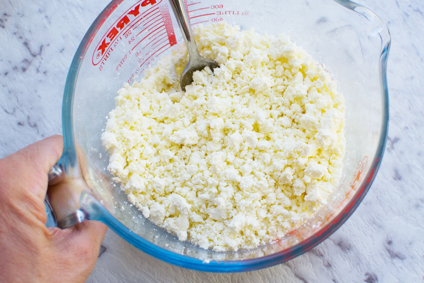 Mashed feta cheese to make mini cheese pies in a Pyrex jug from above